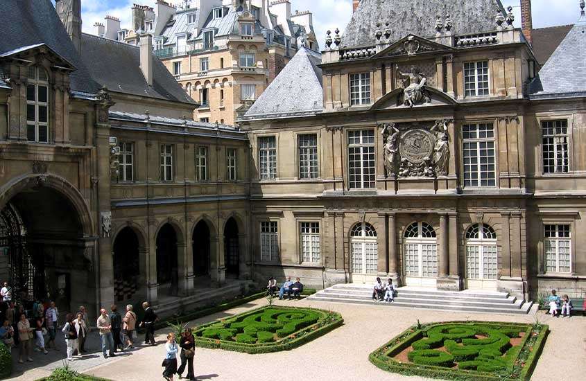 durante um dia ensolarado, pessoas caminhando em jardim em frente a Museu Carnavalet, um dos museus em paris gratuitos