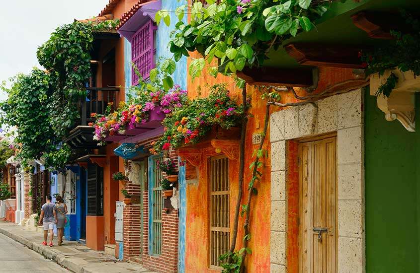 Durante o dia, duas pessoas caminhando em frente a casas coloridas em San Diego, um lugar onde ficar em Cartagena das índias.