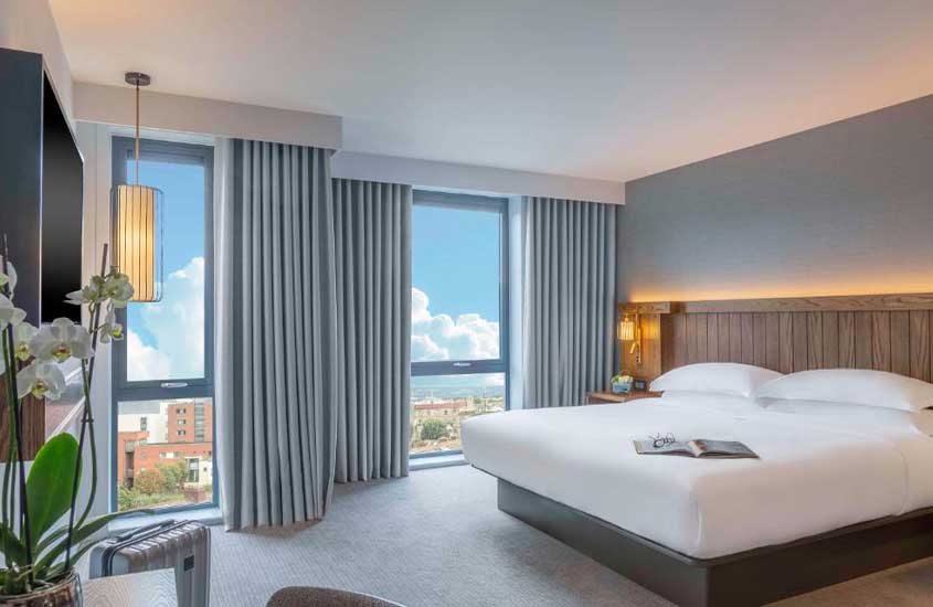 durante o dia, cama de casal em suíte de hotel em Dublin com janelas do chão ao teto com vista para a cidade