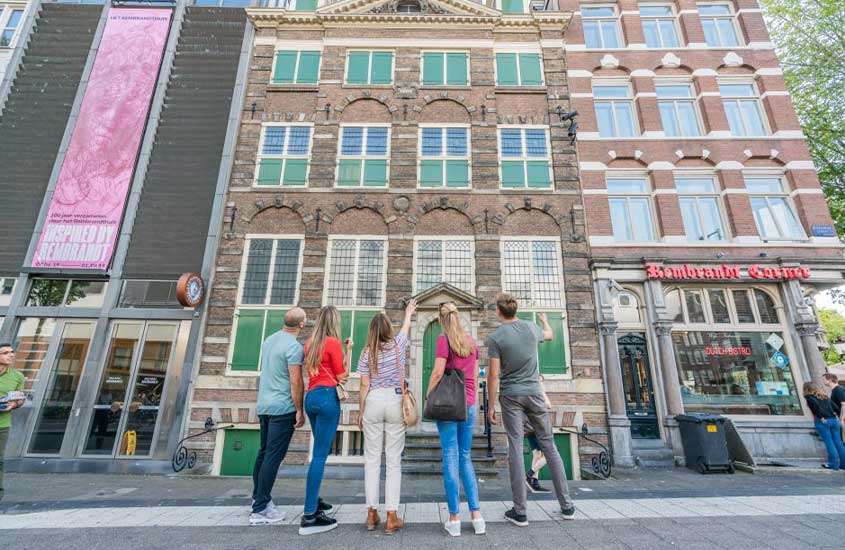 Durante o dia, pessoas de costas observando prédios durante um passeio em Amsterdam