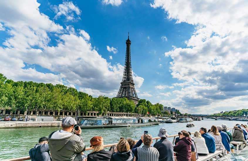 durante o dia, vista panorâmica de pessoas passando em cruzeiro pela Torre Eiffel em um passeio de barco no rio sena paris