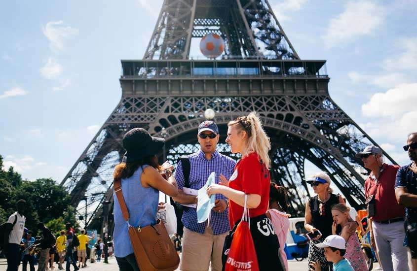 durante o dia, turistas conversando com guia turística em frente a Torre Eiffel, durante tour em paris