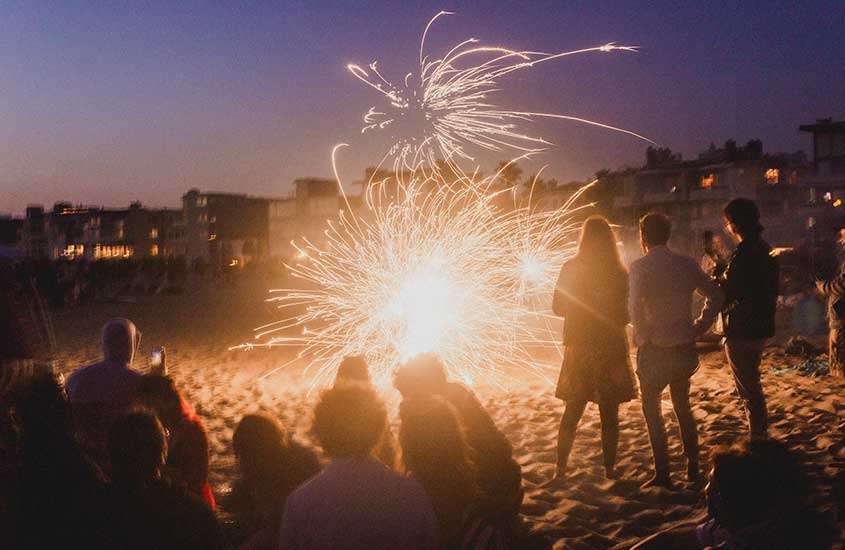 durante a noite, silhueta de pessoas observando fogos de artifício em praia, um lugar onde passar o réveillon em punta del este