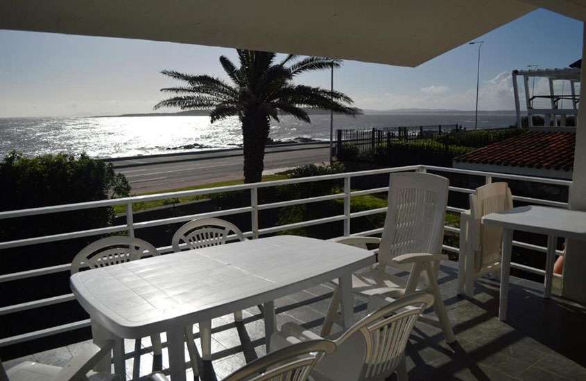 durante um dia ensolarado, cadeiras ao redor de mesa branca em varanda de apartamento com vista para o mar em punta del este