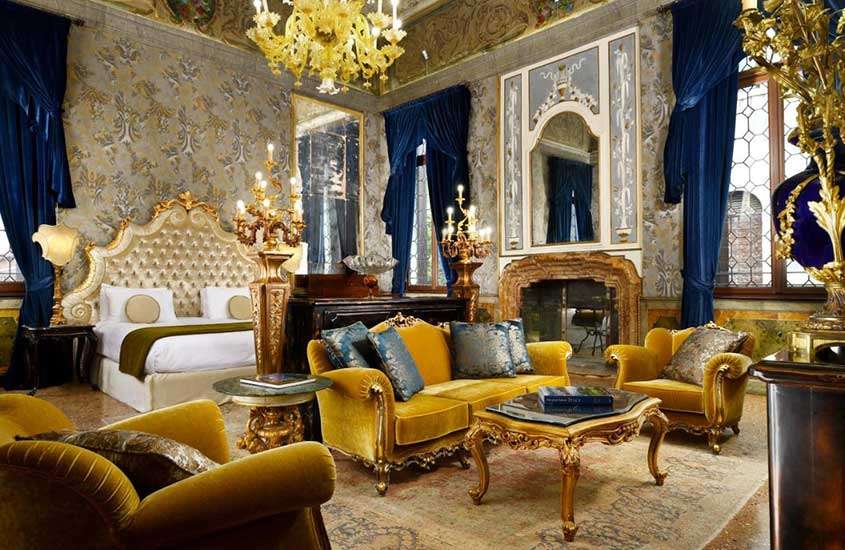 cama de casal, poltronas e mesas venezianos tradicionais, em suíte de hotel elegante