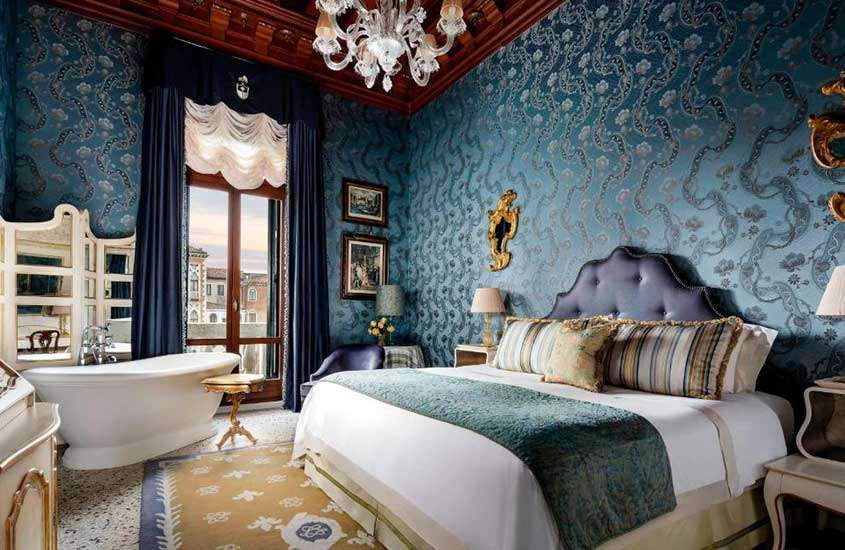 durante o dia, cama de casal e banheira de mármore em suíte de hotel em Veneza com vista da cidade
