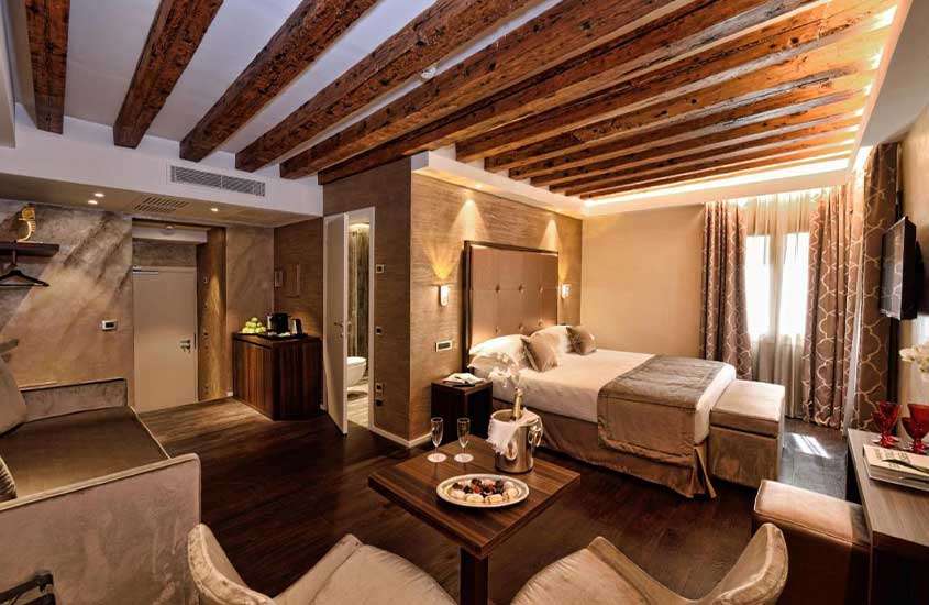 poltronas, sofá, TV e cama de casal em suíte de um dos hotéis em Veneza mais bem avaliados
