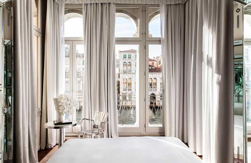 cama de casal em suíte de hotel com janelas panorâmicas e vista dos canais, durante o dia