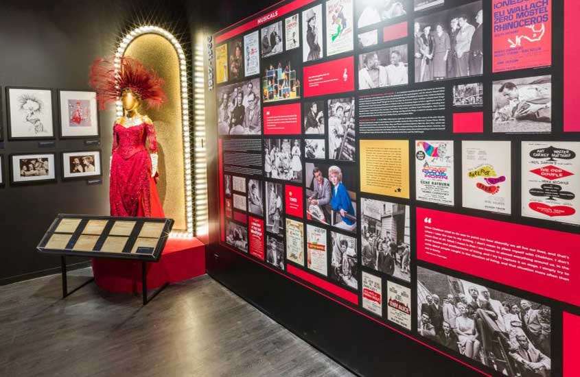 vestido vermelho e diversos quadros e fotografias expostos em interior do Museu da Broadway, um dos museus em Nova York