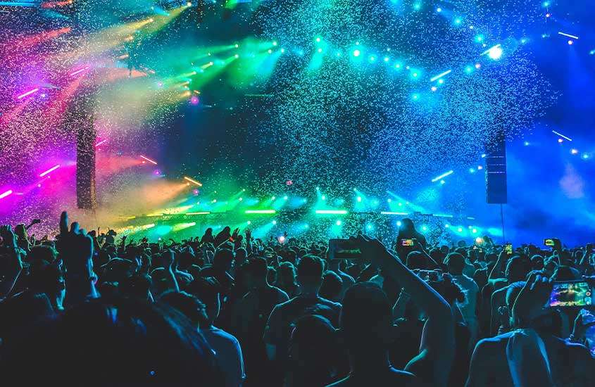 silhueta de pessoas dançando em uma das baladas em Ibiza, iluminada por luzes coloridas.