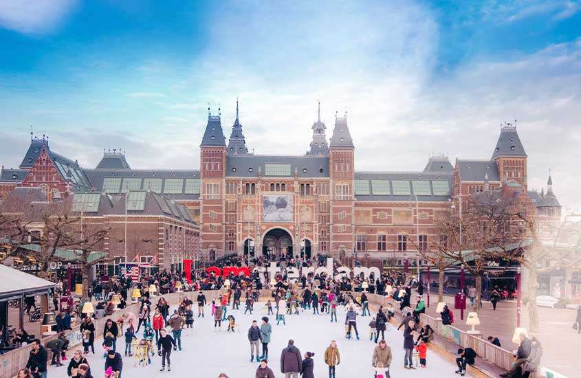 Durante o dia, pessoas em pista de patinação coberta de neve em Museumplein, um lugar para quem busca o que fazer na holanda no inverno