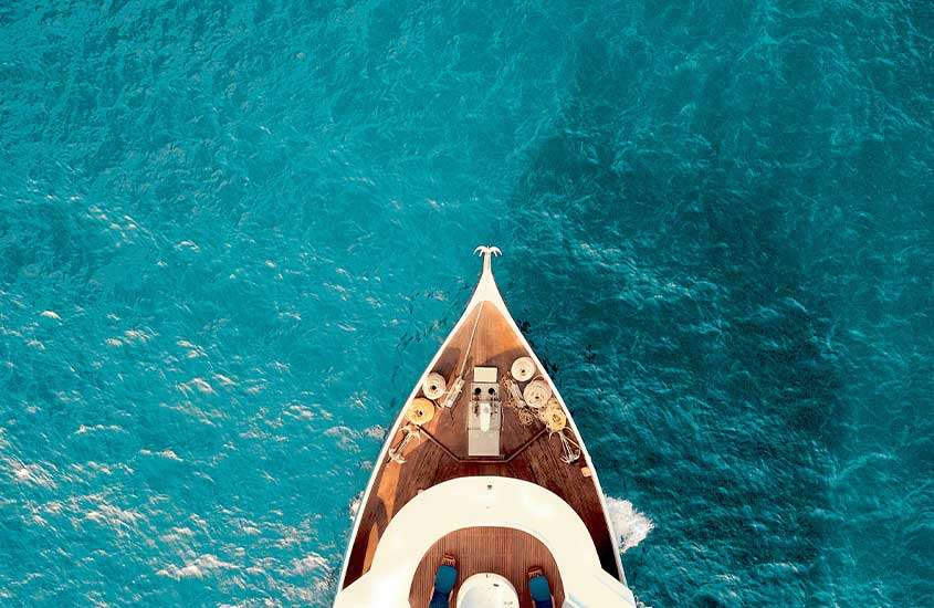 Vista aérea durante um dia ensolarado de um deck de barco em um mar cristalino nas Maldivas, proporcionando uma visão paradisíaca.