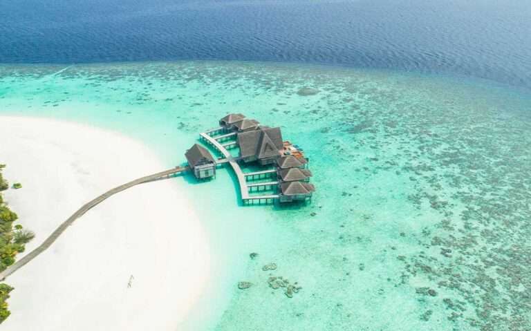 Durante o dia, vista aérea de bangalôs sobre as águas cristalinas de uma das ilhas das Maldivas.