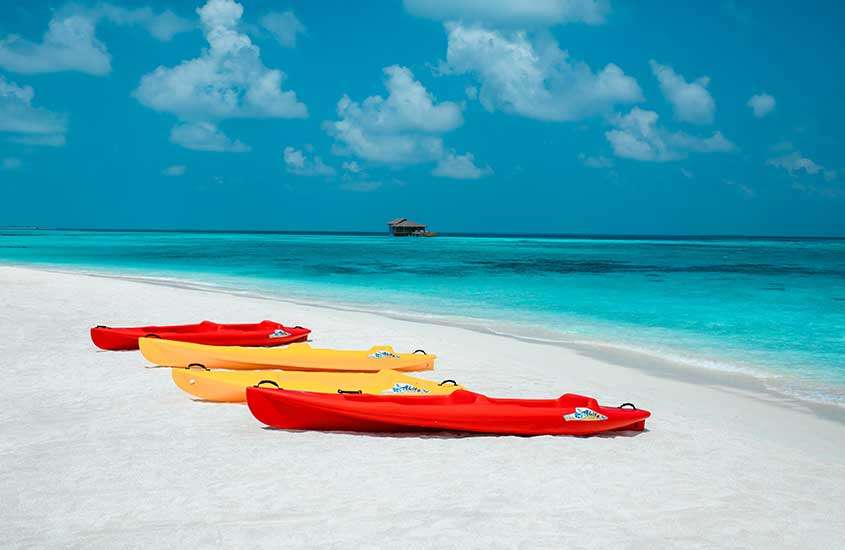 Vista panorâmica durante um dia ensolarado de caiaques laranjas e amarelos na areia de uma bela praia das maldivas.