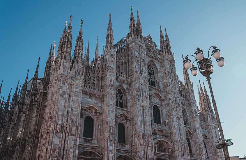 durante o dia, vista de baixo para cima de catedral com arquitetura gótica em Duomo, um lugar onde ficar em Milão.