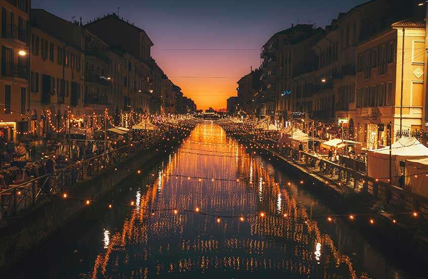 durante anoitecer, diversos barzinhos iluminados às margens de canal em Navigli, um dos melhores lugares para ficar em milão.