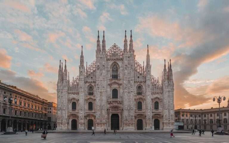 durante entardecer, pessoas caminhando em frente a igreja com estilo gótico em Milão.