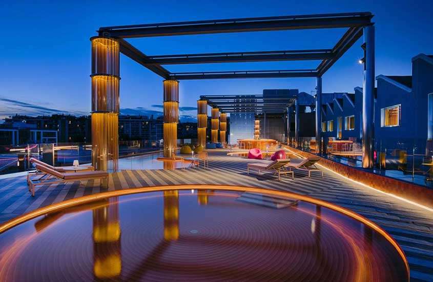 durante anoitecer, espreguiçadeiras e piscinas redondas em cobertura de um dos melhores hotéis em milão.
