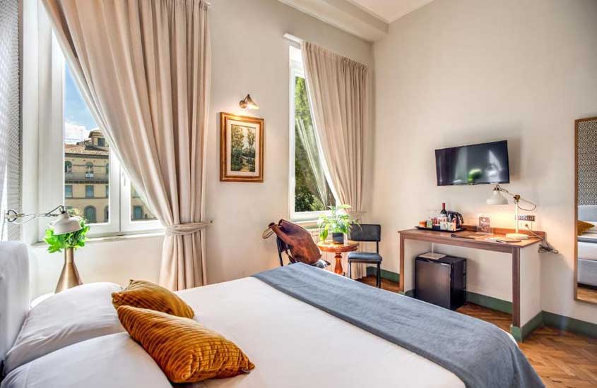 durante o dia, quarto de hotel em Veneza equipado com cama de casal, mesa de escritório, cadeiras e TV em parede e janelas grandes com vista da cidade