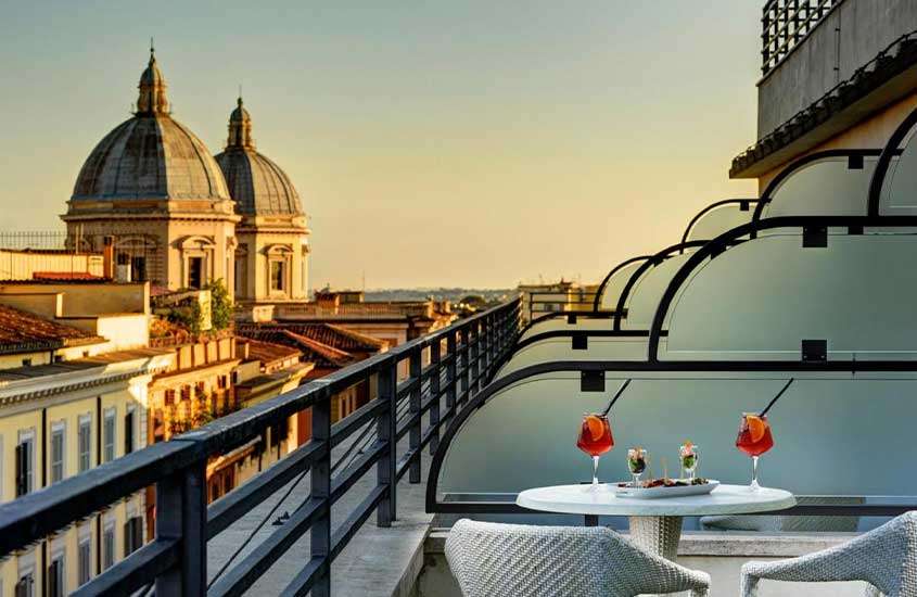 durante um entardecer, mesa e cadeiras em varanda de suíte de hotel em roma com vista para a cidade