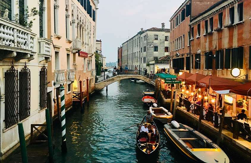 Durante um dia nublado, vista panorâmica de pessoas passando em gôndolas em canal de Castello, um lugar onde ficar em Veneza.