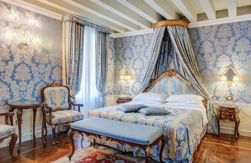 Suíte de hotel em Veneza equipada com poltronas e mesa de madeira, além de cama de casal