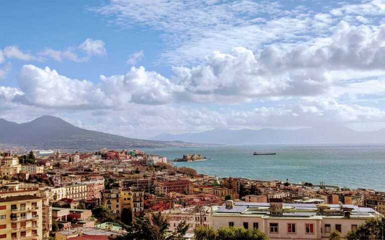 durante o dia com céu azul e alguma nuvens, vista aérea de casas às margens do mar em Nápoles