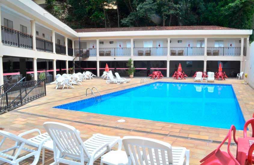 durante o dia, espreguiçadeiras e árvores ao redor de piscina externa de hotel em aguas de lindoia