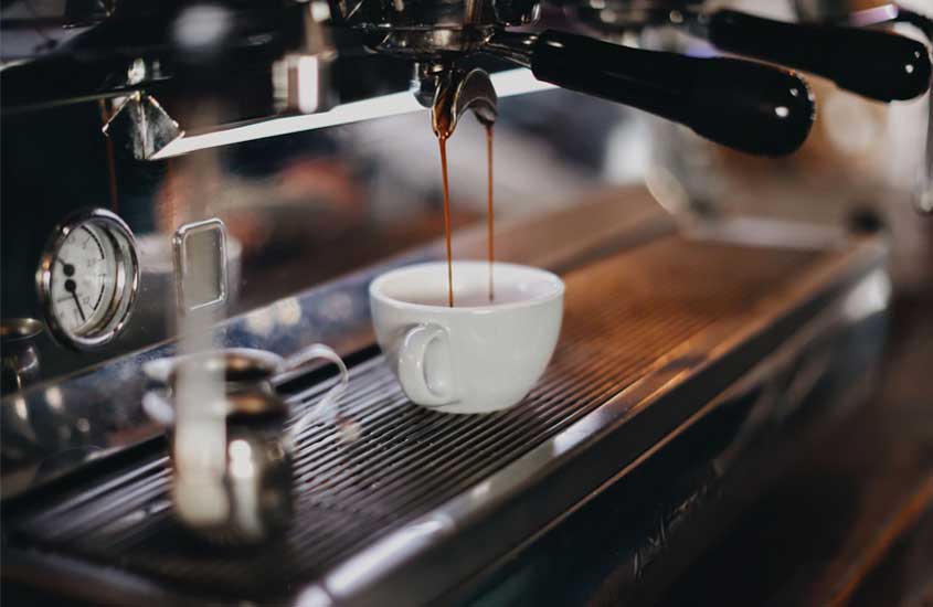máquina de café produzindo café expresso em xícara branca