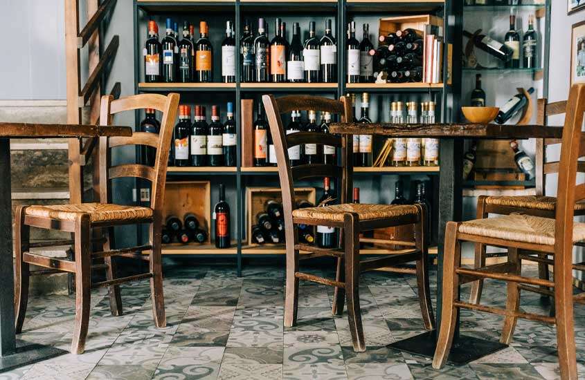 adega de vinhos com mesas e cadeiras de madeira e chão de pedra