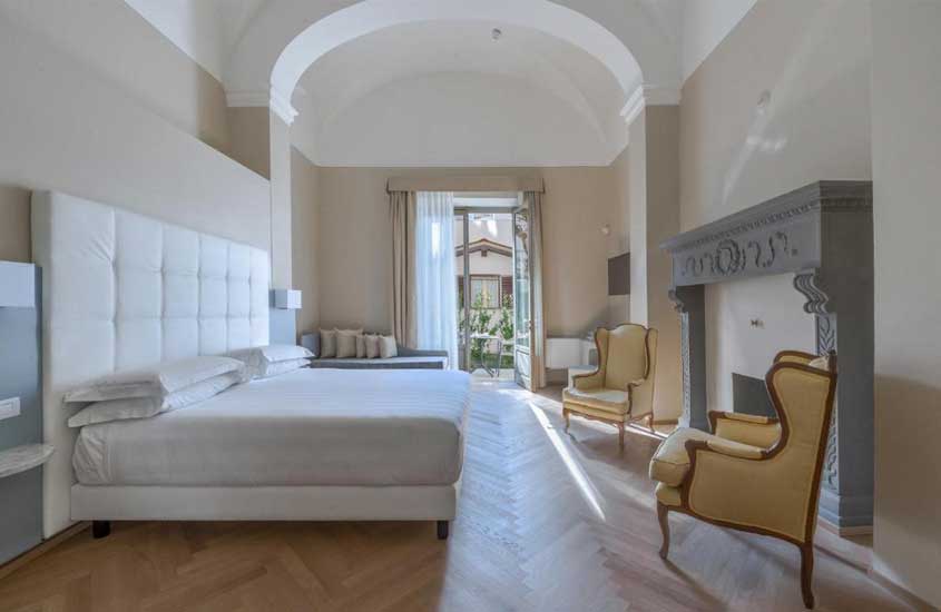 Cama de casal, poltronas e lareira em quarto sofisticado de hotel em Florença