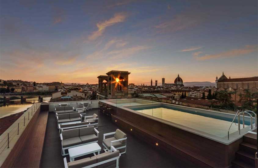 Piscina na cobertura de hotel em Florença, com mesas, cadeiras e vista da cidade ao anoitecer