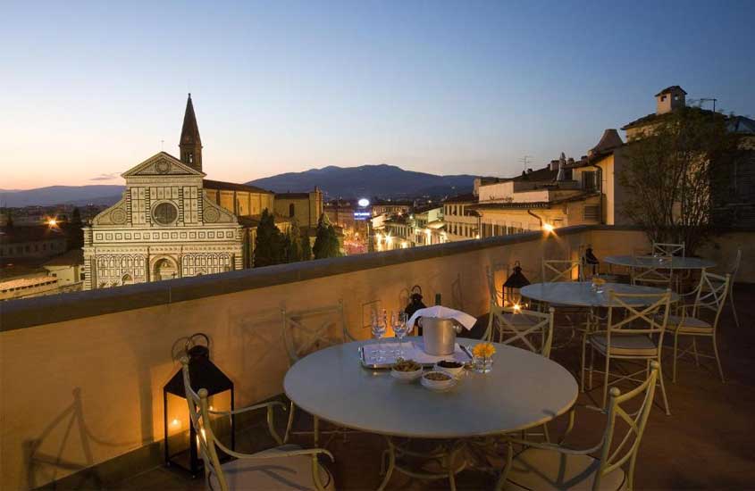 Sacada com mesas, cadeiras, tábua de frios, champagne e vista para a Basílica e horizonte da cidade em um hotel em Florença