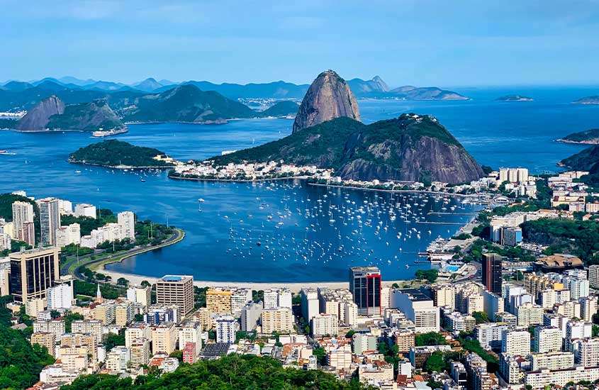 durante o dia, vista aérea de prédios às margens do mar e, no centro, Pão de Açúcar, em Rio de Janeiro, uma das cidades mais bonitas do brasil.
