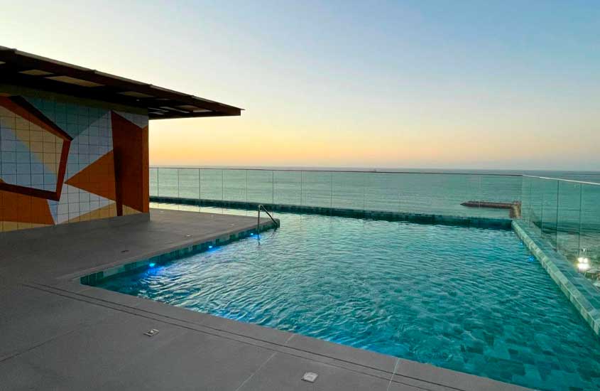 Durante o final de tarde, piscina com borda infinita, vista para o mar e quiosque a esquerda em um dos hotéis em fortaleza beira mar
