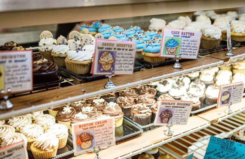 vitrine de cupcakes coloridos e plaquinhas pequenas indicando os sabores