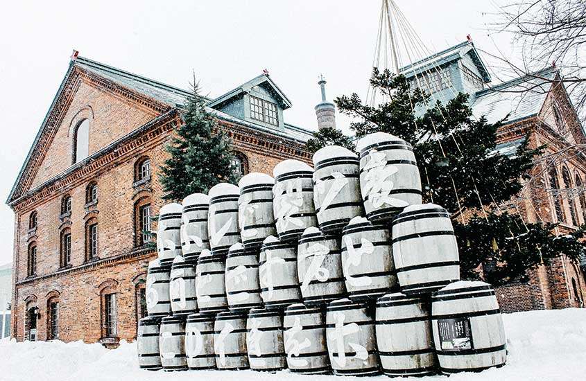 Durante um dia de neve, barris de cerveja em frente a casa grande de tijolos laranjas em Sapporo, um dos principais pontos turísticos no japão