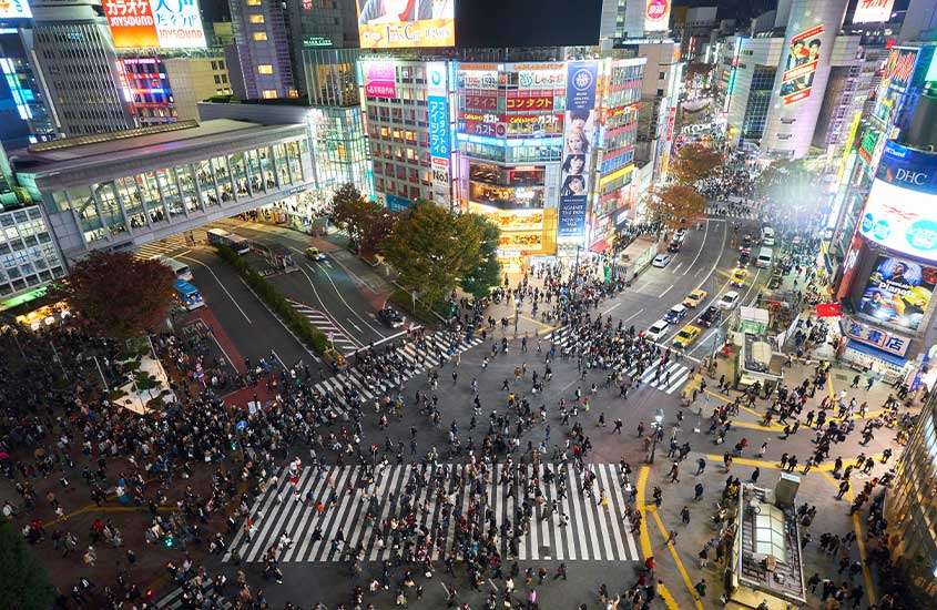Durante a noite, vista aérea de pessoas atravessando o cruzamento de Shibuya