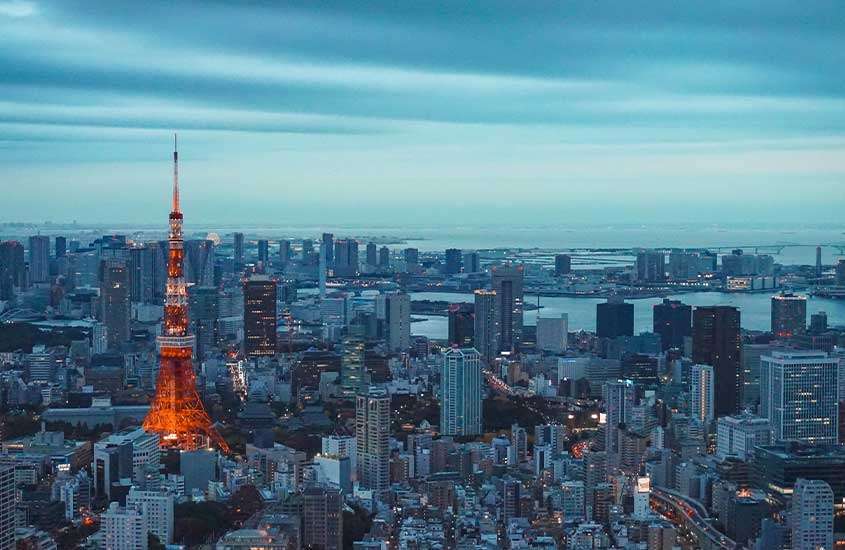 Durante o anoitecer, vista aérea de diversos prédios iluminados em Tokyo, uma das cidades para visitar no Japão