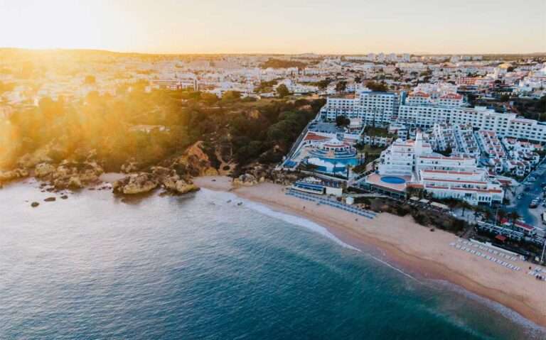 Durante pôr do sol, vista aérea de prédios às margens do mar em Algarve