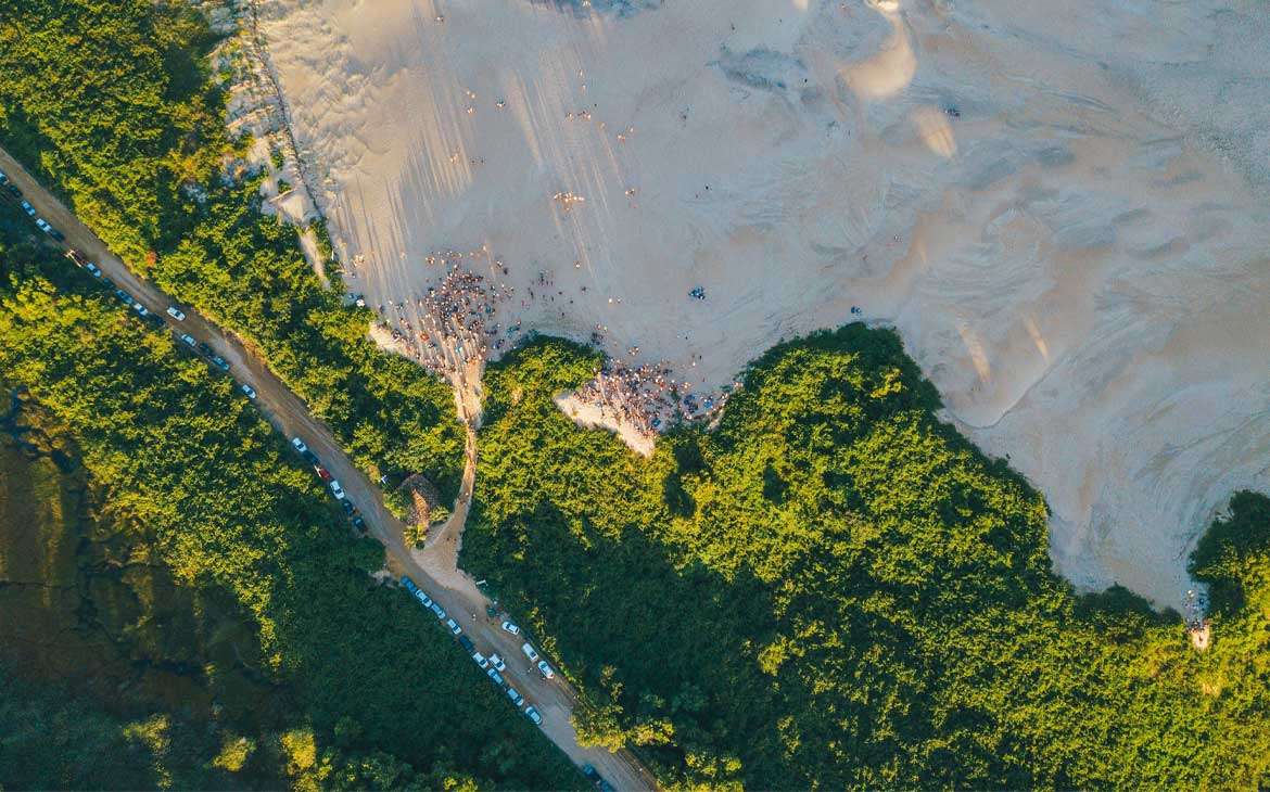 Durante final de tarde, vista aérea de dunas de areia e árvores em Itaúnas ES