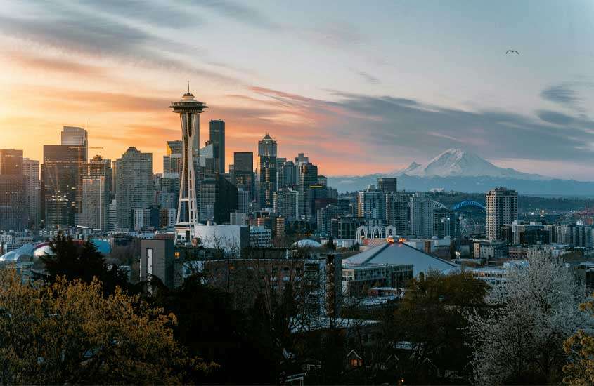 Durante fim de tarde, vista panorâmica de Seattle, cenário de série Grey's Anatomy com prédios altos, montanha no fundo e árvores na frente