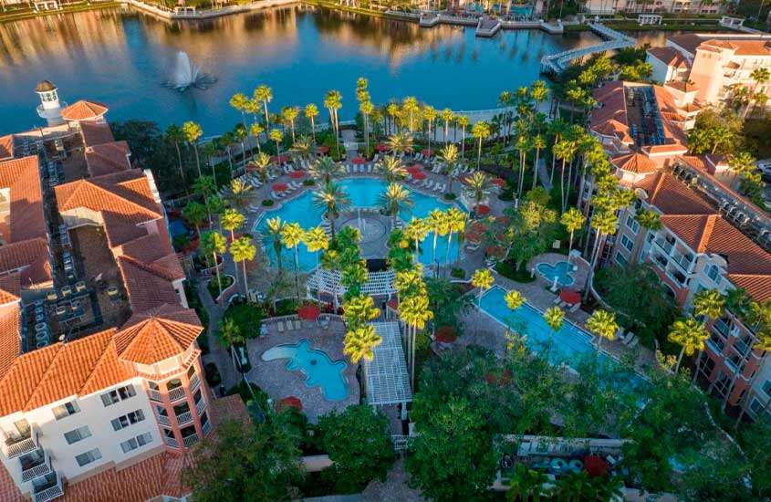 Durante o dia, vista aérea de árvores ao redor de piscina externa de hotel em Orlando com vista para um lago