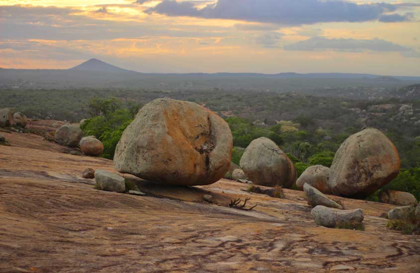 Durante final de tarde, pedras em cima de montanha com vista do horizonte e árvores na frente