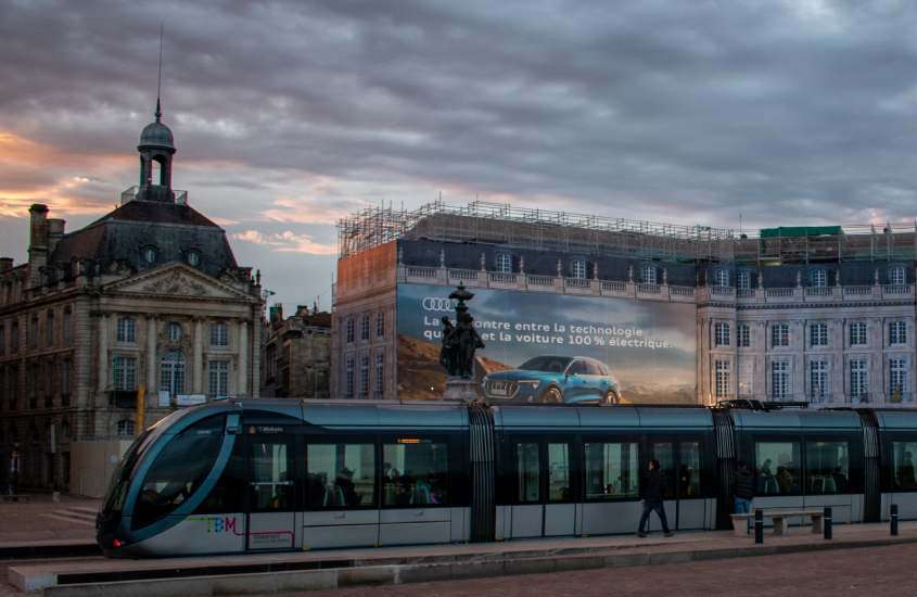 Durante o entardecer, bonde moderno passando em rua de Gare Saint-Jean, um lugar onde ficar em Bordeaux