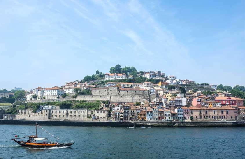 Em dia de sol, casas e prédios coloridos às margens de mar em Vila Nova de Gaia, um lugar onde se hospedar no porto