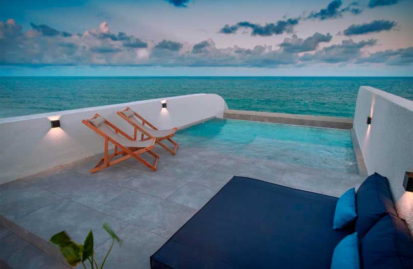 Durante o anoitecer, espreguiçadeiras e piscina externa e privativa em suíte de resort all inclusive para lua de mel com vista para o mar