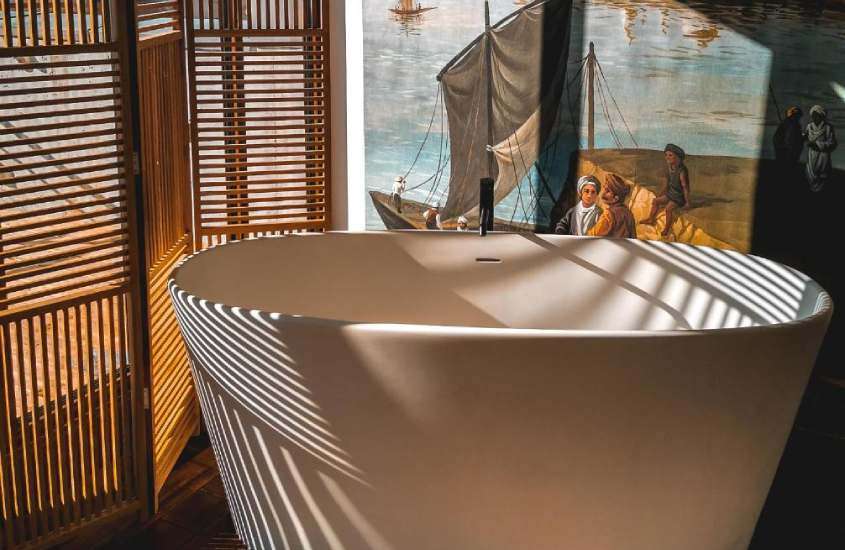 Área de banheiro com banheira parede de madeira e quadro ao lado