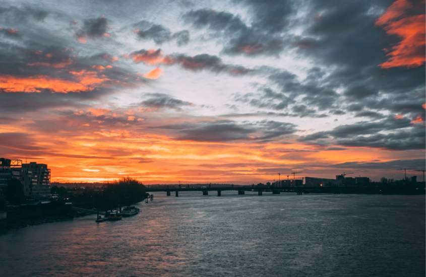 Em pôr do sol, vista panorâmica da ponte em cima do mar com barcos e cidade dos lados