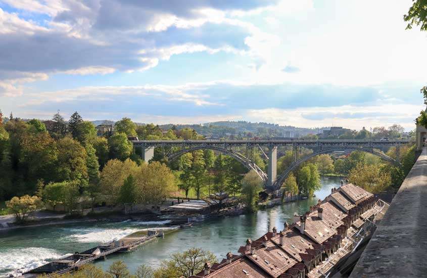 Durante o dia, vista aérea de ponte sobre um rio rodeado por construções e árvores em um bairro onde ficar em Berna
